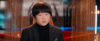 Movie still from “Barb and Star Go to Vista Del Mar” (2021), directed by Josh Greenbaum – A boy in a black jacket and a black shirt; Close Up shot, Low angle