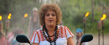 Movie still from “Barb and Star Go to Vista Del Mar” (2021), directed by Josh Greenbaum – A person wearing a necklace; Close Up shot, Low angle
