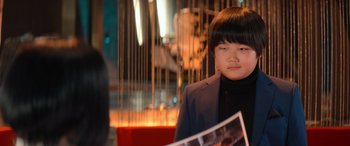 Movie still from “Barb and Star Go to Vista Del Mar” (2021), directed by Josh Greenbaum – A young woman is looking at a magazine; Close Up shot, Over the shoulder angle