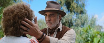 Movie still from “Barb and Star Go to Vista Del Mar” (2021), directed by Josh Greenbaum – An older man wearing a brown hat and a brown vest; Close Up shot, Over the shoulder angle