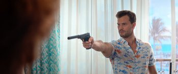Movie still from “Barb and Star Go to Vista Del Mar” (2021), directed by Josh Greenbaum – A man holding a gun in front of a mirror; Medium shot, Over the shoulder angle