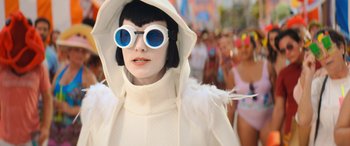 Movie still from “Barb and Star Go to Vista Del Mar” (2021), directed by Josh Greenbaum – A woman in a white outfit and blue sunglasses; Close Up shot, Over the shoulder angle