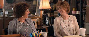Movie still from “Barb and Star Go to Vista Del Mar” (2021), directed by Josh Greenbaum – Two women are sitting at a table talking to each other; Medium shot, Over the shoulder angle