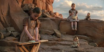 Movie still from “Barbie” (2023), directed by Greta Gerwig – Two little girls sitting and standing on some rocks; Wide shot, Low angle