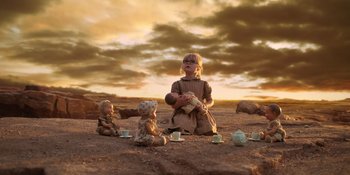 Movie still from “Barbie” (2023), directed by Greta Gerwig – A little girl sitting on the ground holding a teddy bear; Wide shot, Low angle