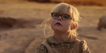 Movie still from “Barbie” (2023), directed by Greta Gerwig – A little girl wearing glasses looking up at the sky; Close Up shot, Over the shoulder angle
