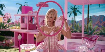 Movie still from “Barbie” (2023), directed by Greta Gerwig – A woman in a pink dress looking into a mirror; Medium shot, Low angle