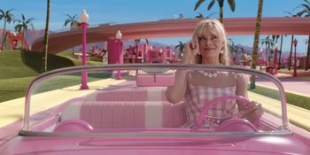 Movie still from “Barbie” (2023), directed by Greta Gerwig – A woman sitting in the back seat of a pink car; Medium shot, High angle