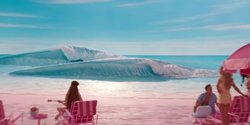 Movie still from “Barbie” (2023), directed by Greta Gerwig – A woman sitting on a chair on the beach looking out at the waves; Extreme Wide shot, High angle