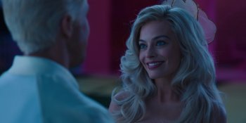 Movie still from “Barbie” (2023), directed by Greta Gerwig – A woman with long blonde hair smiles at a man; Close Up shot, Over the shoulder angle