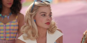 Movie still from “Barbie” (2023), directed by Greta Gerwig – A woman with blonde hair wearing sunglasses and a white shirt; Close Up shot, High angle