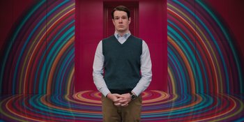 Movie still from “Barbie” (2023), directed by Greta Gerwig – A man standing in front of a colorful background; Medium shot, Low angle