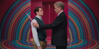 Movie still from “Barbie” (2023), directed by Greta Gerwig – A man in a suit and tie holding a pink object in front of another man in a suit and tie; Medium shot, Low angle