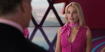 Movie still from “Barbie” (2023), directed by Greta Gerwig – A woman in a pink shirt is looking at a man in a suit; Close Up shot, Over the shoulder angle