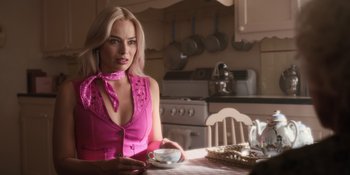 Movie still from “Barbie” (2023), directed by Greta Gerwig – A woman sitting at a table with a cup of tea; Close Up shot, Over the shoulder angle