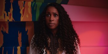 Movie still from “Barbie” (2023), directed by Greta Gerwig – A woman with long black curly hair stares into the camera; Close Up shot, Low angle