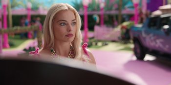Movie still from “Barbie” (2023), directed by Greta Gerwig – A woman with long blonde hair wearing a necklace; Close Up shot, Over the shoulder angle