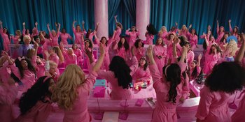 Movie still from “Barbie” (2023), directed by Greta Gerwig – A group of women in pink robes raising their hands in the air; Extreme Wide shot, High angle