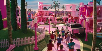 Movie still from “Barbie” (2023), directed by Greta Gerwig – A group of people walking down a street in front of a pink building; Extreme Wide shot, High angle