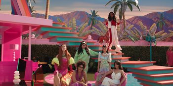 Movie still from “Barbie” (2023), directed by Greta Gerwig – A group of women sitting on pink chairs in front of palm trees; Extreme Wide shot, High angle
