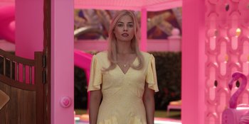 Movie still from “Barbie” (2023), directed by Greta Gerwig – A woman in a yellow dress standing in front of a pink wall; Medium shot, Low angle