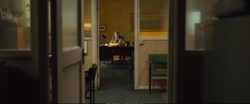 Movie still from “Empire of Light” (2022), directed by Sam Mendes – A man sitting at a table in a room; Wide shot, High angle