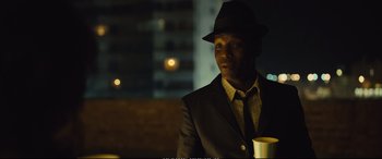 Movie still from “Empire of Light” (2022), directed by Sam Mendes – A man wearing a suit and hat holding a cup; Close Up shot, Over the shoulder angle