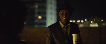 Movie still from “Empire of Light” (2022), directed by Sam Mendes – A man wearing a suit and a hat is holding a cup; Close Up shot, Low angle