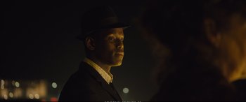 Movie still from “Empire of Light” (2022), directed by Sam Mendes – A man wearing a suit and a hat in the dark; Close Up shot, Over the shoulder angle