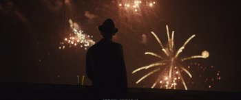 Movie still from “Empire of Light” (2022), directed by Sam Mendes – A man standing in front of fireworks at night; Medium shot, Over the shoulder angle