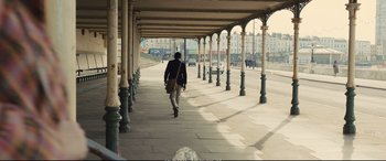 Movie still from “Empire of Light” (2022), directed by Sam Mendes – A man walking down a sidewalk near a street; Wide shot, Low angle
