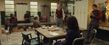 Movie still from “Empire of Light” (2022), directed by Sam Mendes – An older man standing in front of a group of people at a table; Wide shot, Over the shoulder angle