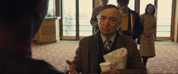 Movie still from “Empire of Light” (2022), directed by Sam Mendes – An older man holding a coffee cup and a newspaper; Medium shot, Over the shoulder angle