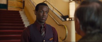 Movie still from “Empire of Light” (2022), directed by Sam Mendes – A man in a vest and tie standing in front of a staircase; Close Up shot, Over the shoulder angle