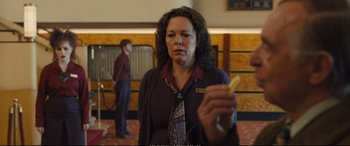 Movie still from “Empire of Light” (2022), directed by Sam Mendes – A woman holding a piece of food in her hand; Close Up shot, Over the shoulder angle