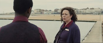 Movie still from “Empire of Light” (2022), directed by Sam Mendes – A woman standing next to a man in front of a body of water; Medium shot, Over the shoulder angle