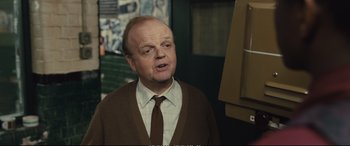 Movie still from “Empire of Light” (2022), directed by Sam Mendes – An older man wearing a brown jacket and a brown tie; Close Up shot, Over the shoulder angle