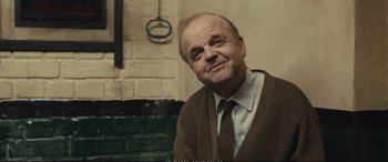 Movie still from “Empire of Light” (2022), directed by Sam Mendes – An older man wearing a brown sweater and a tie; Medium shot, Over the shoulder angle