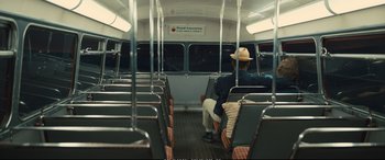 Movie still from “Empire of Light” (2022), directed by Sam Mendes – A person sitting on a bus with a hat on; Wide shot, Over the shoulder angle