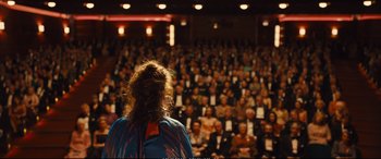 Movie still from “Empire of Light” (2022), directed by Sam Mendes – A woman standing in front of a crowd of people; Wide shot, Over the shoulder angle