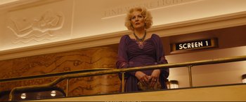 Movie still from “Empire of Light” (2022), directed by Sam Mendes – An older woman in a purple dress standing on a rail; Medium shot, Low angle