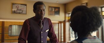 Movie still from “Empire of Light” (2022), directed by Sam Mendes – A man wearing a purple vest and a red tie; Close Up shot, Over the shoulder angle
