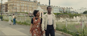 Movie still from “Empire of Light” (2022), directed by Sam Mendes – A man and a woman holding hands while walking down a street; Medium shot, Low angle