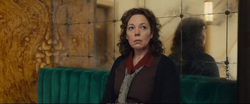 Movie still from “Empire of Light” (2022), directed by Sam Mendes – A woman sitting on top of a couch in a room; Medium shot, Over the shoulder angle