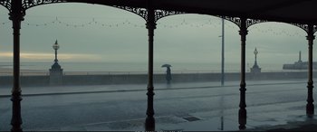 Movie still from “Empire of Light” (2022), directed by Sam Mendes – A person holding an umbrella while standing on a sidewalk; Extreme Wide shot, Low angle