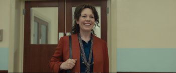 Movie still from “Empire of Light” (2022), directed by Sam Mendes – A woman in a red jacket smiling for the camera; Medium shot, Over the shoulder angle