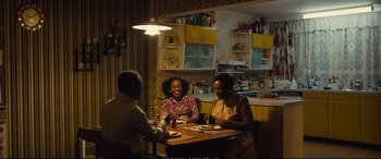 Movie still from “Empire of Light” (2022), directed by Sam Mendes – A group of people sitting at a table in a kitchen; Wide shot, Over the shoulder angle