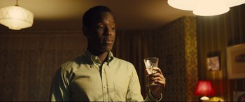 Movie still from “Empire of Light” (2022), directed by Sam Mendes – A man holding a glass of water in his hand; Close Up shot, Over the shoulder angle