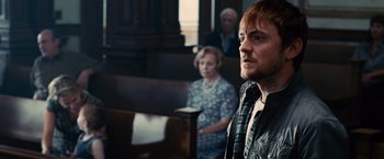 Movie still from “The Judge” (2014), directed by David Dobkin – A man standing in front of an older woman in a church; Close Up shot, Over the shoulder angle