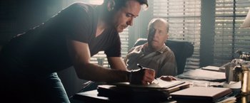 Movie still from “The Judge” (2014), directed by David Dobkin – A man writing on a piece of paper next to an older man; Medium shot, Over the shoulder angle
